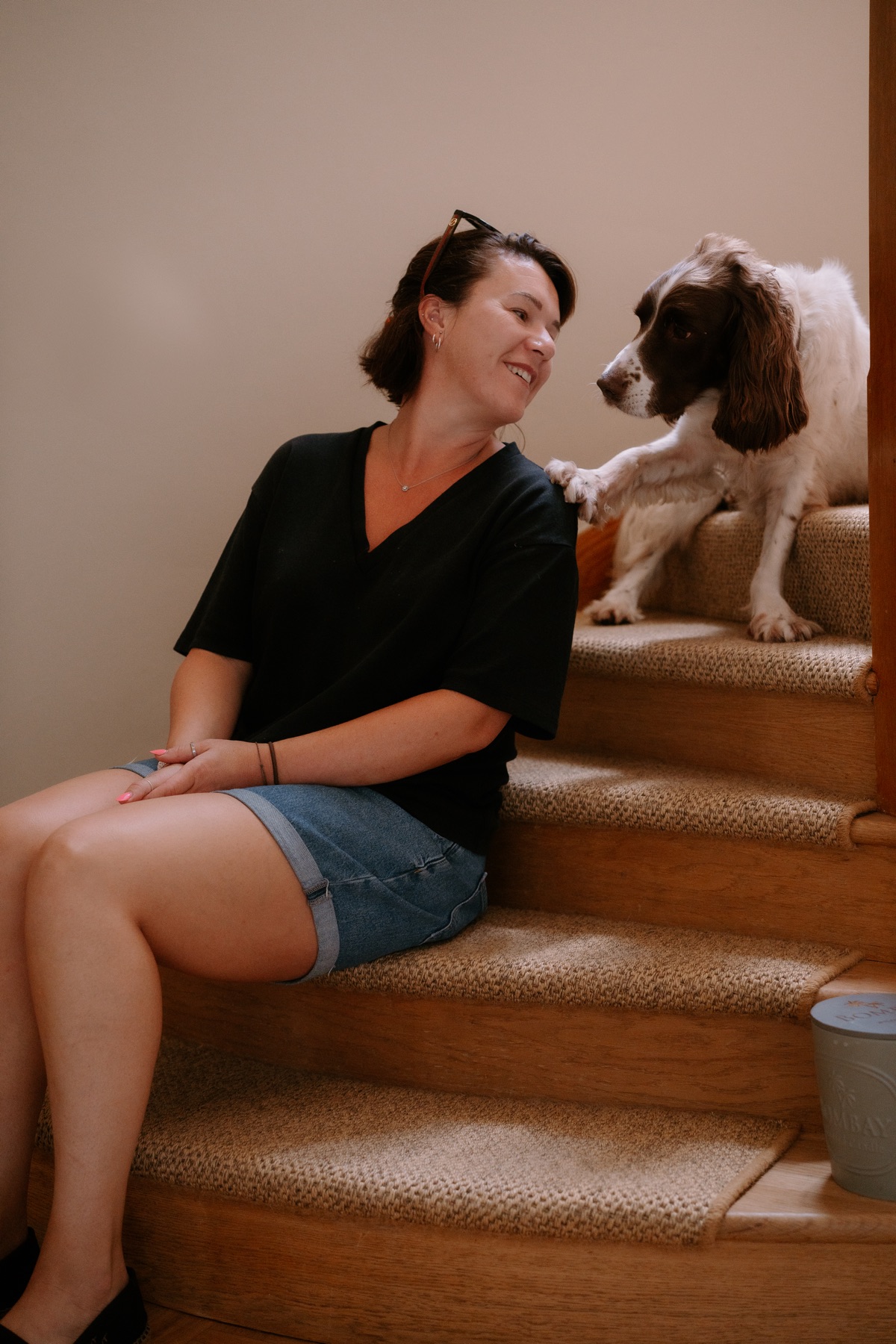 Jodie, founder of Myrtleberry Love, sitting on the stairs with one of her spaniels
